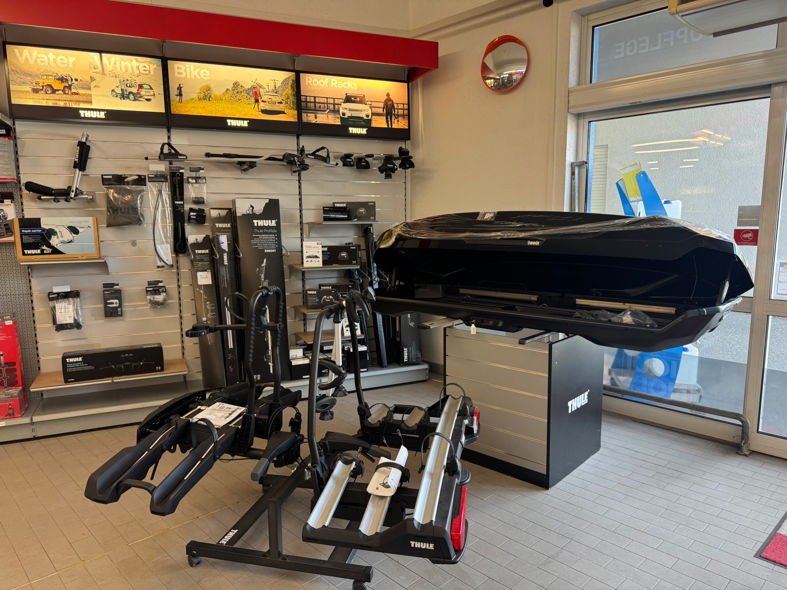 Präsentation von Thule-Fahrradträgern und Dachboxen, mit Wanddisplay für weiteres Zubehör.