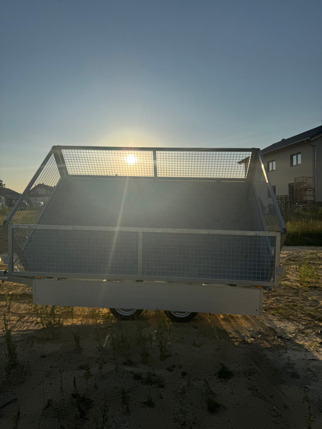 Rückansicht des angekippten Kippanhängers bei tiefstehender Sonne, die Ladefläche wird von hinten beleuchtet.