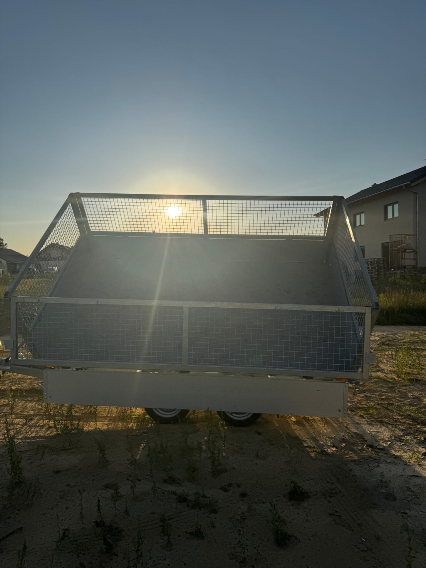 Rückansicht des angekippten Kippanhängers bei tiefstehender Sonne, die Ladefläche wird von hinten beleuchtet.