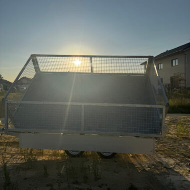 Rückansicht des angekippten Kippanhängers bei tiefstehender Sonne, die Ladefläche wird von hinten beleuchtet.