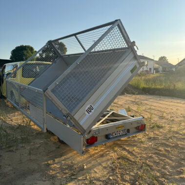 Schrägheckansicht des angekippten Kippanhängers, im Hintergrund ein gelbes Fahrzeug.