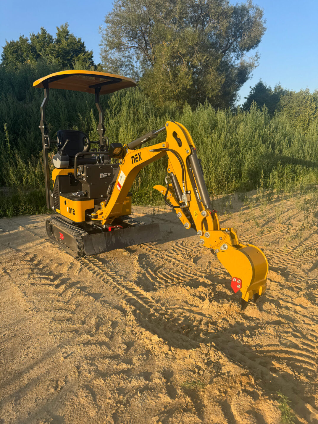 Gelber Kettenbagger mit montierter Schaufel, fotografiert leicht schräg von vorne.