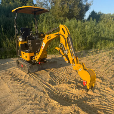 Gelber Kettenbagger mit montierter Schaufel, fotografiert leicht schräg von vorne.