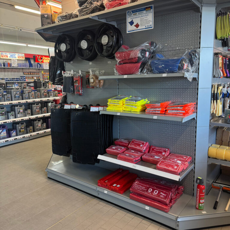 Sortiment mit Warndreiecken, Verbandskästen, Warnwesten, Fußmatten und Radkappen.