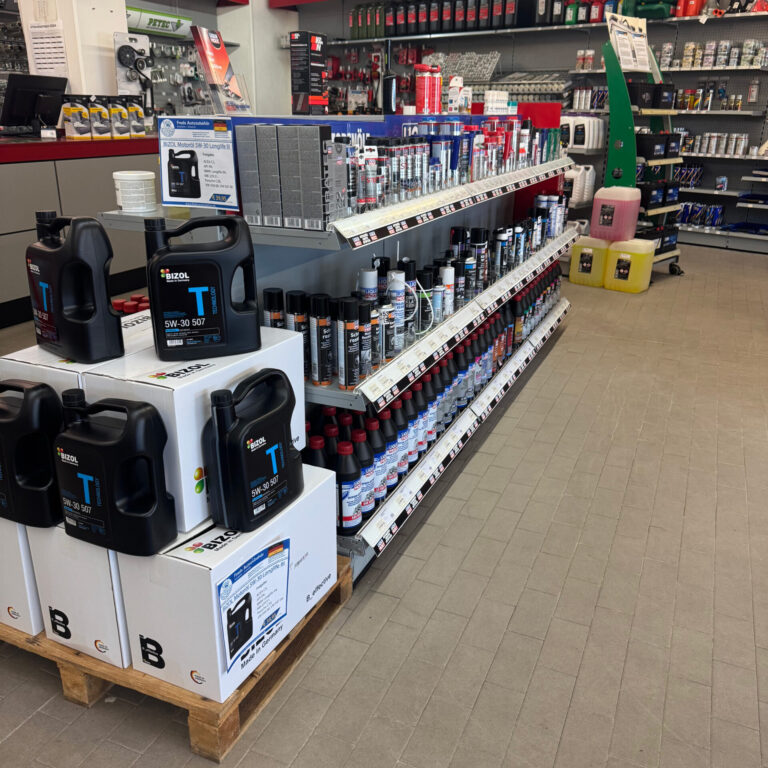 Regal mit Motoröl, Additiven und Spraydosen für Fahrzeugpflege und Wartung.