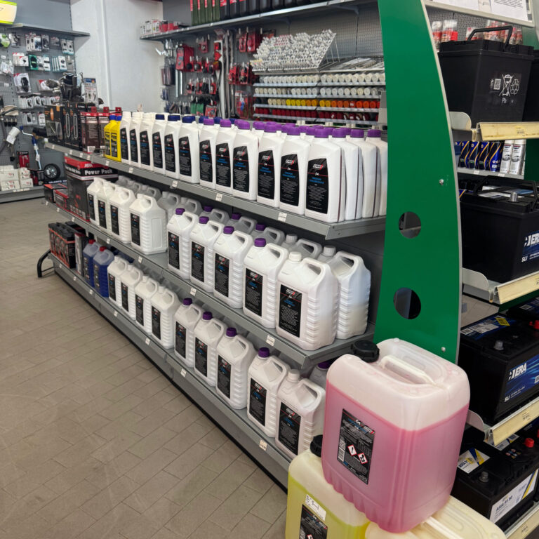 Mehrere Reihen weißer, gelber und pinkfarbener Kanister mit Frostschutz- und Kühlmitteln.