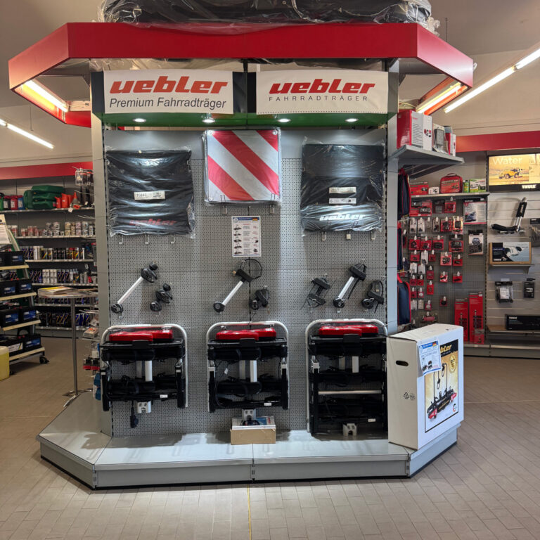 Präsentationsstand mit mehreren Fahrradträgern der Marke Uebler und passenden Zubehörteilen.
