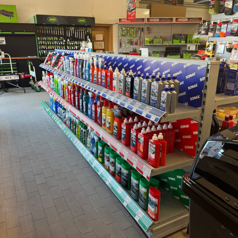 Nahansicht eines Regals mit verschiedenen Sonax-Autopflegeprodukten in farbigen Flaschen.